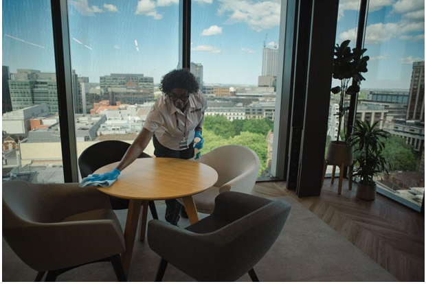 A commercial cleaner cleaning a table in an office.