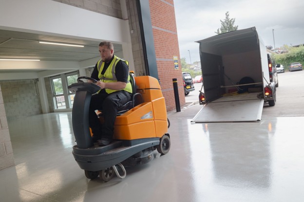 Industrial Deep Cleaning being carried out in a commercial facility using a ride-on floor cleaning machine.